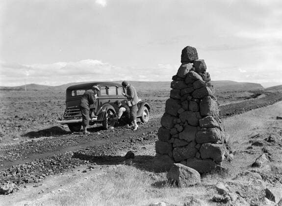 Poll photo collection. Iceland. AutoPech. A defective tire is changed. In the foreground a lot artfully stacked stones as a road deficit in snow. 1934. Iceland Copyright: xpiemagsx pienatarchpart630102021-18629 !ACHTUNG AUFNAHMEDATUM GESCHÄTZT!