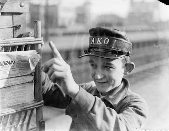 Poll photo collection. Reporting Dutch Railways. Young magazine seller of the Ako points to mobile kiosk. 1932. Amsterdam, Noord-Holland Copyright: xpiemagsx pienatarchpart630102021-21990 !ACHTUNG AUFNAHMEDATUM GESCHÄTZT!