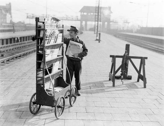 Poll photo collection. Reporting Dutch Railways. Young magazine seller of the Ako standing at mobile kiosk on platform. 1932. Amsterdam, Noord-Holland Copyright: xpiemagsx pienatarchpart630102021-21991 !ACHTUNG AUFNAHMEDATUM GESCHÄTZT!