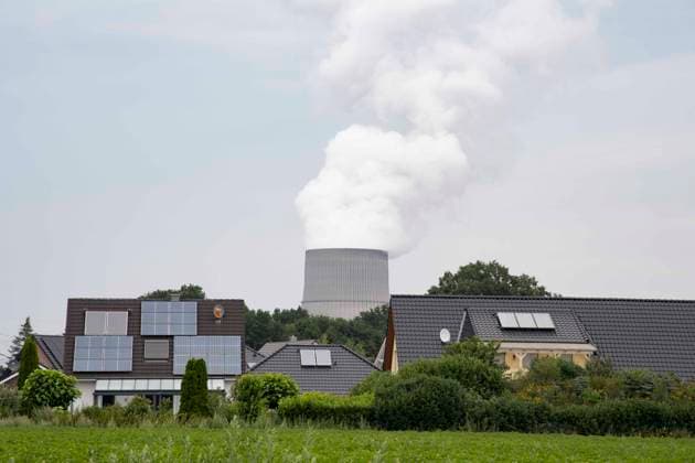 Blick auf das Atomkraftwerk Emsland mit Kuehlturm, im Vordergrund eine Wohnsiedlung, auf den Hausdaechern sind Solarmodule, Photovoltaik-Anlagen, Das Kernkraftwerk Emsland in Lingen ist eins vcn drei Atomkraftwerken in Deutschland, die noch bis zum Jahresende Strom liefern sollen, und ueber deren Weiterbetrieb debattiert wird, Lingen am 31.07.2022. *** View of the nuclear power plant Emsland with cooling tower, in the foreground a housing estate, on the house roofs are solar modules, photovoltaic systems, The nuclear power plant Emsland in Lingen is one of three nuclear power plants in Germany, which should still supply electricity until the end of the year, and about whose continued operation is debated, Lingen on 31 07 2022