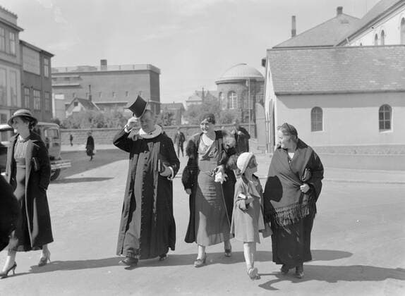 Poll photo collection. Iceland. Reykjavik. The pastor of the Domkerk in talaim with folding cycle and top hat with a woman and youngest child after the Sunday morning service on the way home. On the right the southern portal of the Domkerk. 1934. Iceland, Reykjavik Copyright: xpiemagsx pienatarchpart72010201-45261 !ACHTUNG AUFNAHMEDATUM GESCHÄTZT!