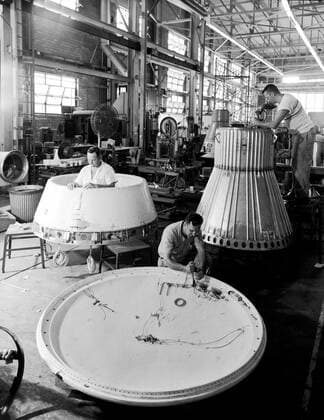 Assembling the Little Joe capsules. The capsules were manufactured in-house by Langley technicians. Three capsules are shown here in various stages of assembly. The escape tower and rocket motors shown on the completed capsule would be removed before shipping and finally assembly for launching at Wallops Island. Joseph Shortal wrote (vol. 3, p. 32): Design of the Little Joe capsules began at Langley before McDonnell started on the design of the Mercury capsule and was, therefore, a separate design. Although it was not designed to carry a man, it did have to carry a monkey. It had to meet the weight and center of gravity requirements of Mercury and withstand the same aerodynamic loads during the exit trajectory. Although in comparison Copyright: xpiemagsx piemagsspace-663 !ACHTUNG AUFNAHMEDATUM GESCHÄTZT!