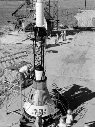 Technicians attach the escape tower to the Mercury capsule prior to assembly with Little Joe launcher, August 20, 1959. Joseph Shortal describe this as follows (vol. 3., p. 33): The escape tower and rocket motors were taken from the Mercury capsule production. The tower is shown being attached to the capsule.... The escape rocket was a Grand Central 1-KS-52000 motor with three canted nozzles. The tower-jettison motor was an Atlantic Research Corp. 1.4-KS-785 motor. This was the same design tested in a beach abort test...and had the offset thrust line as used in the beach abort test to insure that the capsule would get away from the booster in an emergency. The escape system weighed 1,015 pounds, including 236 pounds of ballast for stabili Copyright: xpiemagsx piemagsspace-675 !ACHTUNG AUFNAHMEDATUM GESCHÄTZT!