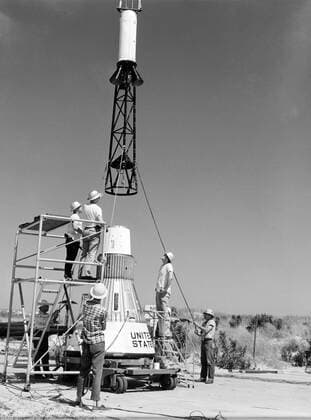 Technicians attach the escape tower to the Mercury capsule prior to assembly with Little Joe launcher, August 20, 1959. Joseph Shortal describe this as follows (vol. 3., p. 33): The escape tower and rocket motors were taken from the Mercury capsule production. The tower is shown being attached to the capsule.... The escape rocket was a Grand Central 1-KS-52000 motor with three canted nozzles. The tower-jettison motor was an Atlantic Research Corp. 1.4-KS-785 motor. This was the same design tested in a beach abort test...and had the offset thrust line as used in the beach abort test to insure that the capsule would get away from the booster in an emergency. The escape system weighed 1,015 pounds, including 236 pounds of ballast for stabili Copyright: xpiemagsx piemagsspace-676 !ACHTUNG AUFNAHMEDATUM GESCHÄTZT!