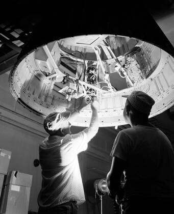 Technicians adjust the rocket motor during the attachment of the escape tower to the Mercury capsule prior to assembly with Little Joe launcher, August 20, 1959. Joseph Shortal wrote (vol. 3., p. 33): The escape tower and rocket motors were taken from the Mercury capsule production. The tower is shown being attached to the capsule.... The escape rocket was a Grand Central 1-KS-52000 motor with three canted nozzles. The tower-jettison motor was an Atlantic Research Corp. 1.4-KS-785 motor. This was the same design tested in a beach abort test...and had the offset thrust line as used in the beach abort test to insure that the capsule would get away from the booster in an emergency. The escape system weighed 1,015 pounds, including 236 pounds Copyright: xpiemagsx piemagsspace-678 !ACHTUNG AUFNAHMEDATUM GESCHÄTZT!