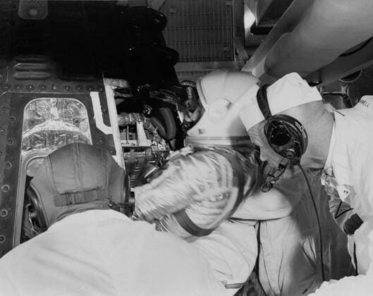 S61-02881 (1961) --- Astronaut Virgil I. (Gus) Grissom, suited up in a newly designed pressure suit, is assisted as he climbs into Liberty Bell 7 spacecraft. Behind him backup pilot John Glenn watches the insertion. The Mercury-Redstone 4 (MR-4) mission was scrubbed a few hours later due to unfavorable weather over the launch pad. Copyright: xpiemagsx piemagsspace-865 !ACHTUNG AUFNAHMEDATUM GESCHÄTZT!