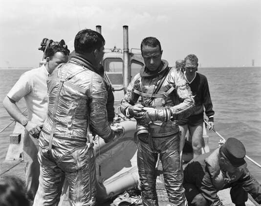 S62-01355 (1962) --- Project Mercury astronauts M. Scott Carpenter, prime pilot of the Mercury-Atlas 7 (MA-7) spaceflight, prepares to go through a water egress test. Astronaut Walter M. Schirra (back to camera), the backup MA-7 pilot is also present. Carpenter and Schirra are in the Mercury pressure suit, without the helmet. Behind them is an inflated life raft. Copyright: xpiemagsx piemagsspace-909 !ACHTUNG AUFNAHMEDATUM GESCHÄTZT!