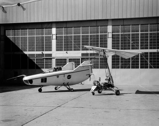 In this photo of the M2-F1 lifting body and the Paresev 1B on the ramp, the viewer sees two vehicles representing different approaches to building a research craft to simulate a spacecraft able to land on the ground instead of splashing down in the ocean as the Mercury capsules did. The M2-F1 was a lifting body, a shape able to re-enter from orbit and land. The Paresev (Paraglider Research Vehicle) used a Rogallo wing that could be (but never was) used to replace a conventional parachute for landing a capsule-type spacecraft, allowing it to make a controlled landing on the ground. Copyright: xpiemagsx piemagsspace-1137 !ACHTUNG AUFNAHMEDATUM GESCHÄTZT!