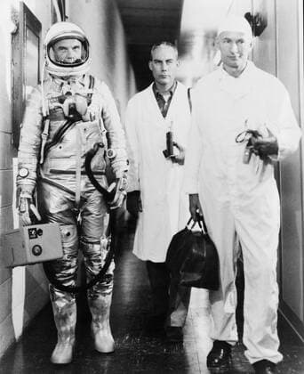 S62-00377 (20 Feb. 1962) --- Astronaut John H. Glenn Jr., walking out of building with Dr. William K. Douglas (to Glenn s left), and Joe W. Schmitt, NASA s suit technician (in front of Dr. Douglas). This Mercury Atlas 6 (MA-6) Friendship 7 flight marks America s first manned Earth-orbiting spaceflight. Copyright: xpiemagsx piemagsspace-39487 !ACHTUNG AUFNAHMEDATUM GESCHÄTZT!