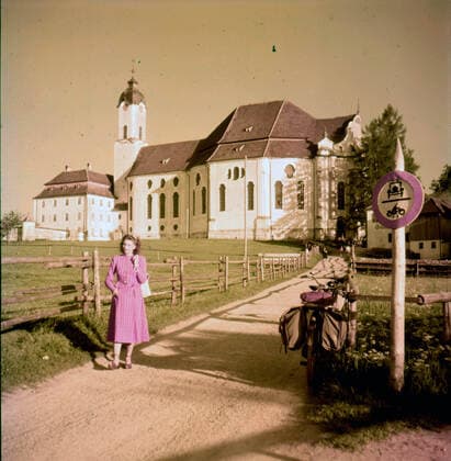 Circa 1946, Obersalzberg, Germany: Girl with bicycle and panniers stands in the road at a church near the Platterhof, seat of Nazi government in time of Hitler s residence at mountain resort. Obersalzberg Germany - ZUMAk09_ 19460402_zka_k09_998 Copyright: xKeystonexUSAx