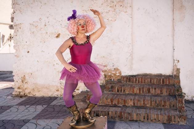 Full body of mature female mime artist in tutu and pink wig with bright makeup standing on pedestal with raised arm and looking away JavierBallester_GiraGiraClown_17.jpg Copyright: xJavierxBallesterx Model Released