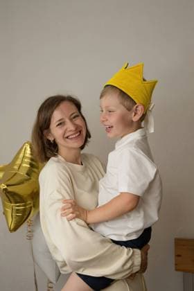 Creative Highlights Symbolbilder Smiling mother holding little boy in a crown looking at camera at a birthday party at home, Model released, Property released LiliyaSolopova_DariaAndGordeyBirthday_00015.jpg Copyright: xLiliyaxSolopovax MR
