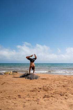 IMAGO Creative: Neue Aussichten Back view of unrecognizable shirtless male doing Adho Mukha Vriksasana on stone against waving sea and cloudy sky during yoga session on sandy beach in summer, Model released MiguelCano_AcroyogaCalblanque_00005.jpg Copyright: xMiguelxCanox MR