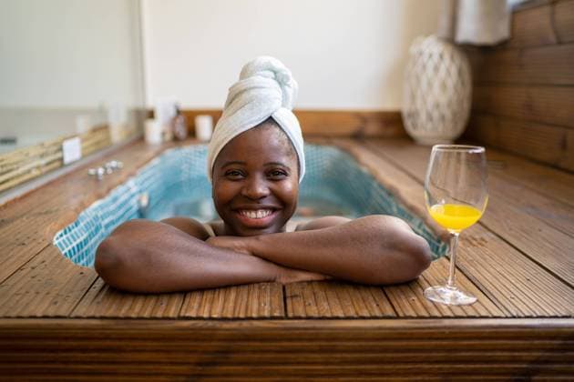 Creative Highlights Symbolbilder Cheerful black woman with a towel covering her head smiling looking at camera inside a jacuzzi near glass with orange juice, Model released OscarDeDios_AlgarveWithBea_8.jpg Copyright: xOscarxDexDiosx MR