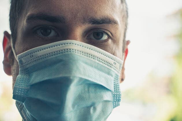 junger Mann mit medizinischer Op Maske im Sommer Urlaub. Schutz vor Covid-19 Coronavirus Infektion