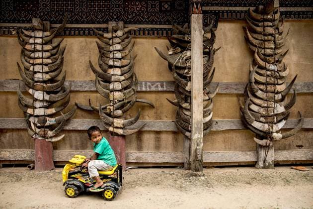IMAGO Cultures of the world, Toraja Volk in Indonesien (220817) -- TANAH TORAJA, Aug. 17, 2022 -- A boy rides a toy car near a house displaying buffalo s horn in Tanah Toraja of South Sulawesi, Indonesia, Aug. 17, 2022. (Photo by Xinhua) INDONESIA-TANAH TORAJA-DAILY LIFE GarryxLotulung 