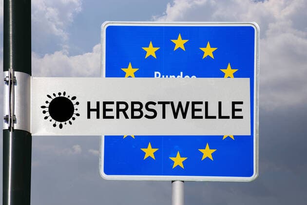 Symbolbild Herbstwelle: Straßenschild mit der Aufschrift Herbstwelle vor einem deutschen Grenzschild
