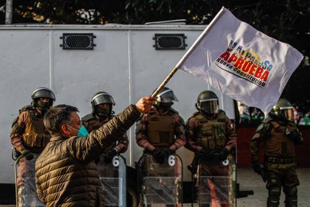 August 19, 2022, Valparaiso, Chile: A counter-demonstrator raises a flag for the approval of a new constitution as police stand guard in the background during the protest. Demonstrators take to the streets of Valparaiso in rejection of a new constitution with some counter-demonstrators in support of the new constitution in Valparaiso. Valparaiso Chile - ZUMAs197 20220819_zaa_s197_159 Copyright: xCristobalxBasaurexArayax