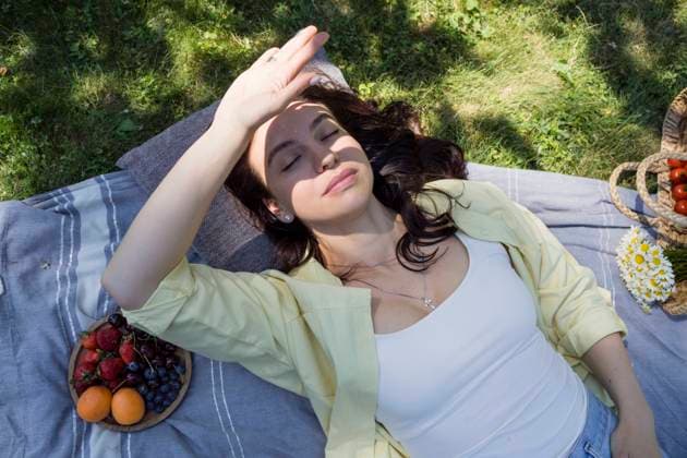 Woman shielding eyes with hand lying at park model released, Symbolfoto, OSF00524