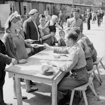 A Polish family registering at No.17 Displaced Persons Assembly Centre in Hamburg Zoological Gardens, 18 May 1945. The Displaced Persons camp within the grounds of Hamburg Zoo was build by the Blohm & Voss company during WWII to house the forced labourers that worked in their factory. The camp was taken over by the British on 5 May 1945 and quickly given over as an arrivals centre for displaced persons. On arrival displaced persons were organised into groups of 50 for processing through the reception centre. They were dusted with anti-louse powder and given a registration card (D.P.3) bearing such details as their name, nationality and place of residence. All were then allotted a bed in one of the accommodation huts. In times of overflow a Copyright: xpiemagsx warofficeww2pie5222-145 !ACHTUNG AUFNAHMEDATUM GESCHÄTZT!