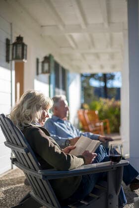 An elderly woman reads a book while she enjoys a glass of wine. United States, Nevada, Stateline CR_TFBM220825-1029652-01 ,model released, Symbolfoto