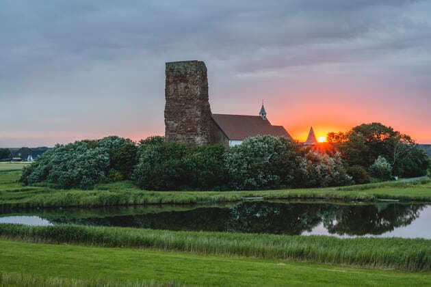 Germany, Schleswig-Holstein, Pellworm, Lake in front of Old Church of Saint Salvator at sunrise, KEBF02379
