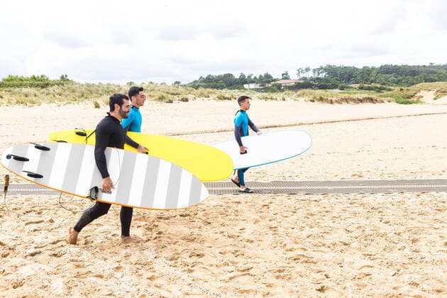 IMAGO Creative: Welttourismustag am 27. September Side view of positive fit young ethnic male friends with dark hair in wetsuits holding surfboards and walking on sandy beach before surfing on sunny day, Model released DavidBenito_SurfFriends_1 Copyright: xDavidxBenitox MR