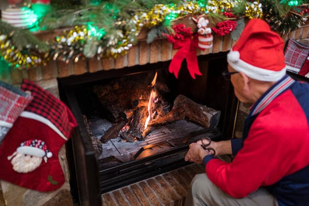 From above of male in Santa hat lighting fireplace with heap of firewood in light room with decorations during Christmas holidays, Model released JuanAlbertoRuiz_ID493_19781_031 Copyright: xJuanxAlbertoxRuizx MR