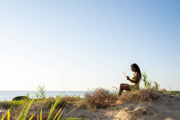 IMAGO Creative: Welttourismustag am 27. September Side view of African American woman in stylish dress and sunglasses browsing tablet while spending time on grassy seacoast in summer OscarDeDios_ID517_20397_008 Copyright: xOscarxDexDiosx Model Released