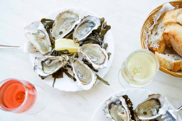 Raw oysters served in a french restaurant Raw oysters served in a french restaurant with lemon slices, wine, baguette and butter Copyright: xAsyaxNurullinax AN061118-6