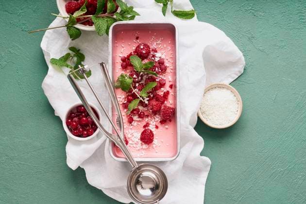 Pink ice cream with raspberries and red currants Pink ice cream with raspberries and red currants on green background. Top view Copyright: xAsyaxNurullinax AN250120-31