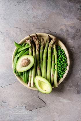 Young Green asparagus Variety of raw uncooked organic young green vegetables asparagus, peas, pod pea, avocado in ceramic plate over grey texture table background. Top view, space. Healthy eating Copyright: xNatashaxBreenx NB090418-22
