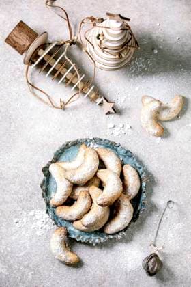 Christmas shortcrust cookies vanilla crescents with wooden decorations. Top view Homemade traditional Christmas shortcrust cookies vanilla crescents with icing sugar. On ceramic plate with wooden xmas decorations over light grey background. Copyright: xNatashaxBreenx NB221120-3