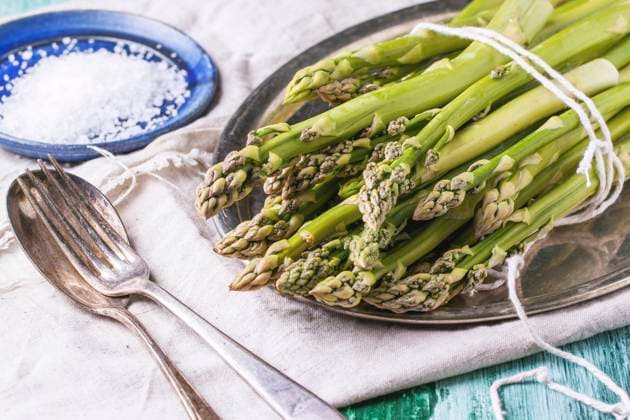 Bunch of young green asparagus on vintage tray served with ceramic plate of sea salt and silver cutlery over green wooden table. Copyright: xNatashaxBreenx xThexPicturexPantryx NB_IMG_8059