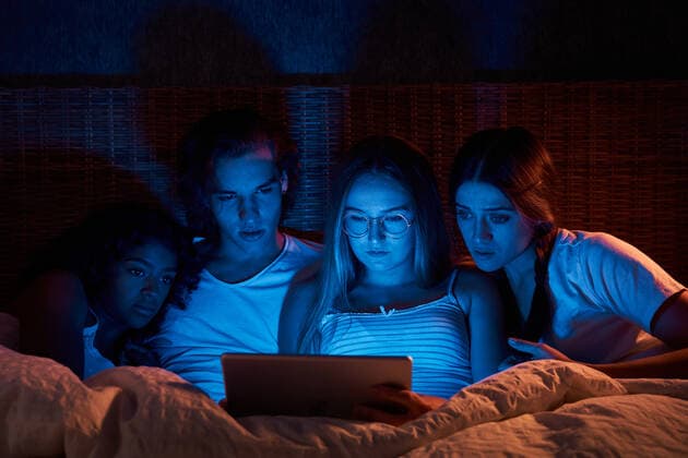 Frightened young friends in sleepwear watching horror on tablet while lying together on comfy bed at night, Model released, Property released ManuelRuiz_FlatmatesMusiciansTerrace_91 Copyright: xManuelxRuizx MR
