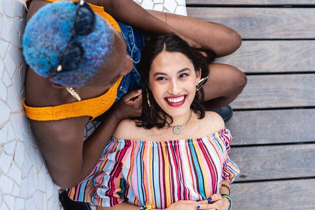 Creative Highlights Symbolbilder From above pretty Asian female smiling and lying on lap of African American girlfriend while relaxing on bench in park and looking at each other, Model released RafaCortes_LesbianEthnicCouple_23 Copyright: xRafaxCortesx MR