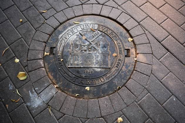 Tartu, Estland - August 23, 2022: Kanaldeckel mit Burg in der Strasse. Tartu Estland *** Tartu, Estonia August 23, 2022 manhole cover with castle in street Tartu Estonia 
