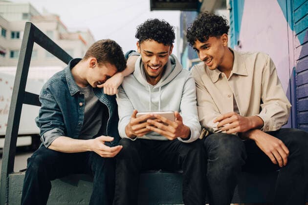 Happy man using smart phone while sitting with friends outdoors Sweden, Stockholm, model released Copyright: xMaskot,xMaskotxBildbyraxABx , MA95040 MA95040