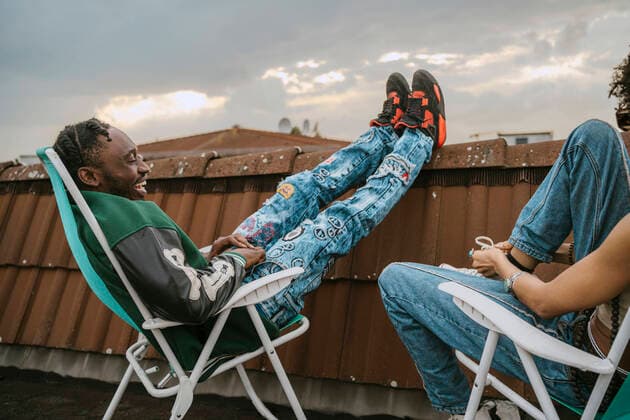 Creative Highlights Symbolbilder Side view of cheerful young man talking with female friend while sitting on chair at rooftop Germany, Berlin, model released, property released Copyright: xMaskot,xMaskotxBildbyraxABx , MA95108 MA95108