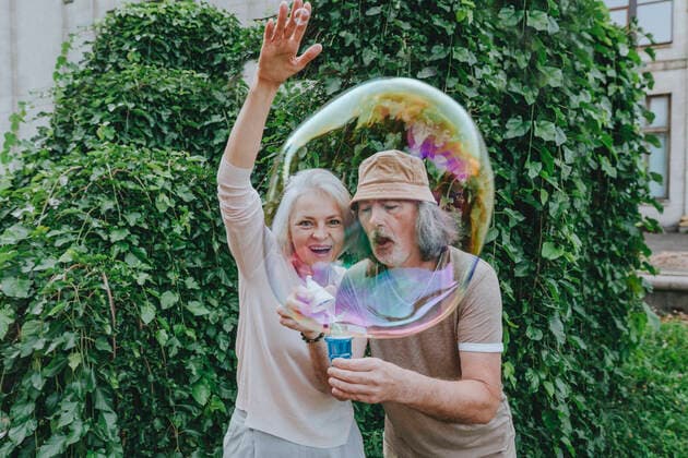Creative Highlights Symbolbilder Happy mature woman enjoying by senior man making bubbles in park model released Symbolfoto YTF00034