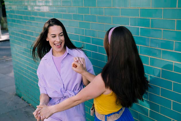 Creative Highlights Symbolbilder Happy friends dancing with each other near brick wall model released, Symbolfoto, AMWF00800