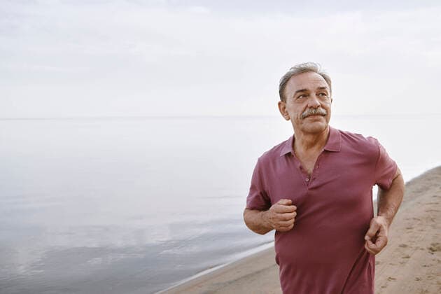 Thoughtful senior man running by sea at beach model released, Symbolfoto, AZF00467