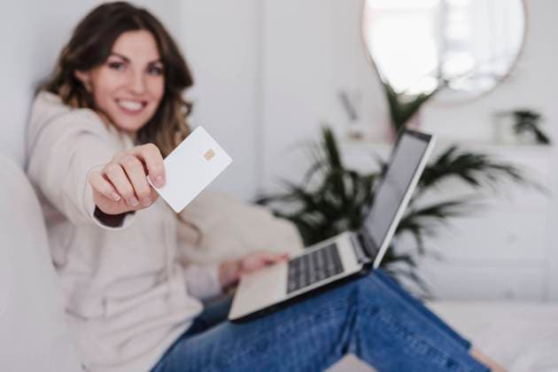 Smiling young woman with laptop showing credit card model released, Symbolfoto property released, EBBF06019