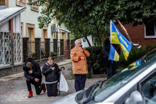 PERECHYN, UKRAINE - SEPTEMBER 25, 2022 - People kneel to show respect to Senior Lieutenant Armen Petrosian, 50, who died while liberating the northeastern Kharkiv Region from Russian occupation troops as the convoy with the coffin moves through Perechyn, Zakarpattia Region, western Ukraine. Funeral ceremony of Senior Lieutenant Armen Petrosian in Perechyn  Copyright: xSerhiixHudakx