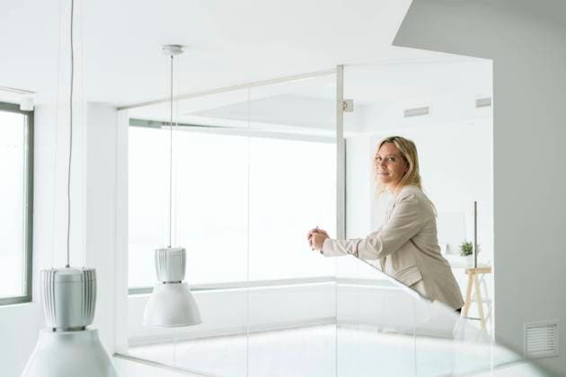 Businesswoman leaning on railing in minimalist office corridor model released, Symbolfoto property released, EBBF06220