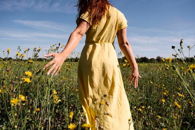 Creative Highlights Symbolbilder Woman in yellow dress walking amidst flowers model released, Symbolfoto, EYAF02111