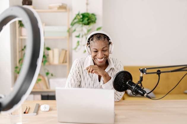 Smiling freelancer wearing wireless headphones recording podcast at table in home office model released, Symbolfoto property released, JCZF01094