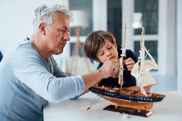 Grandfather and grandson with ship model on table at home model released, Symbolfoto property released, JOSEF12114