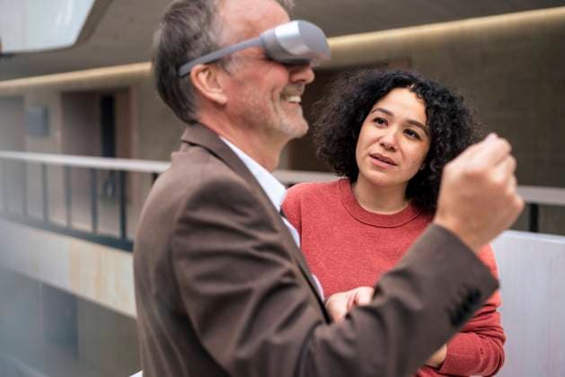 IMAGO Creative: Business - Progressive Geschäftsmodelle Businesswoman looking at happy colleague wearing VR glasses in corridor model released, Symbolfoto property released, JOSEF12557