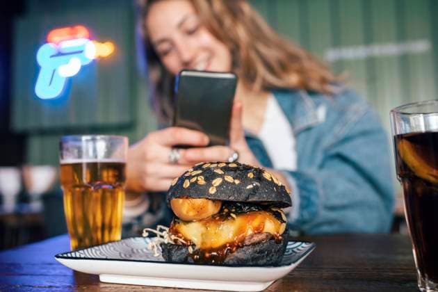 Young woman photographing burger through smart phone at restaurant model released, Symbolfoto property released, JSRF02205